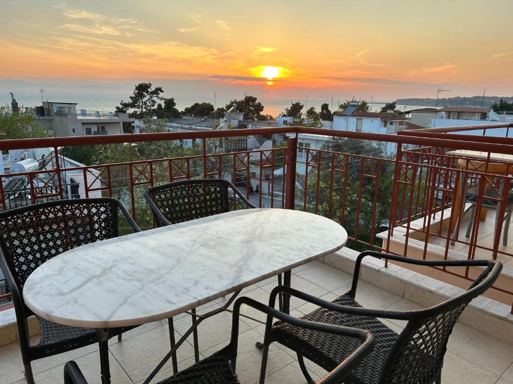 a table and chairs on a balcony with a sunset at LighthouZe87 in Nea Michaniona