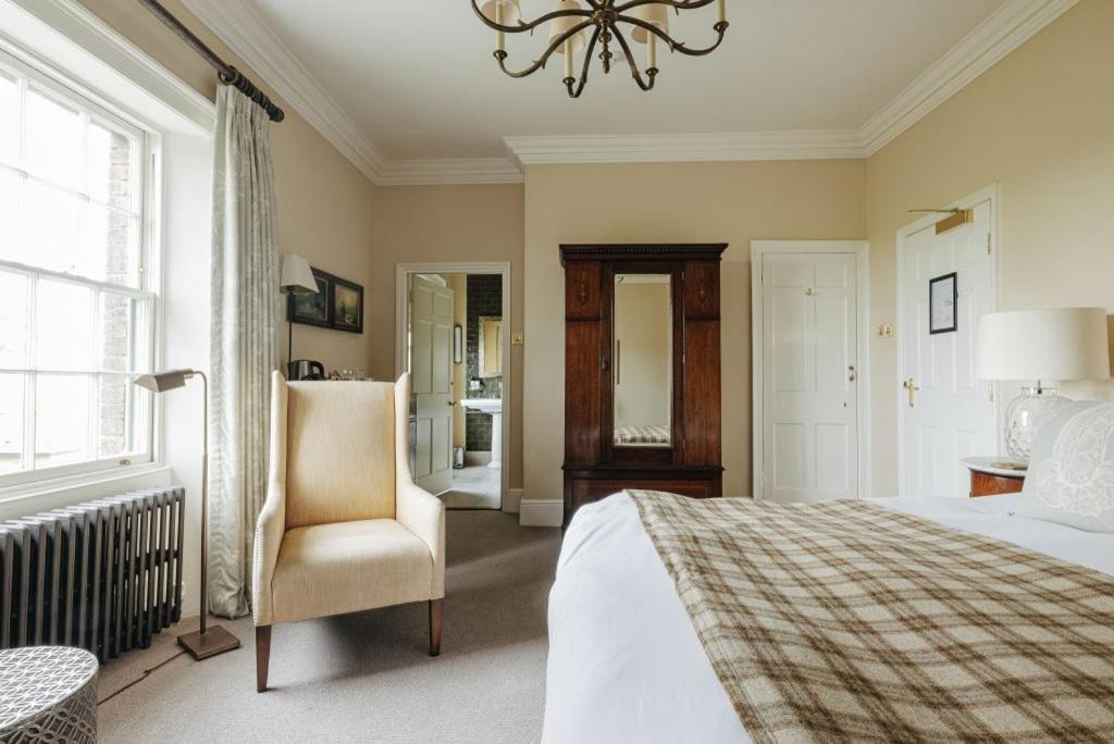 a bedroom with a bed and a chair and a chandelier at Victoria in Holkham