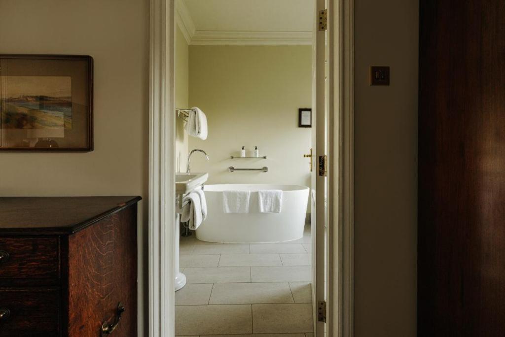 a bathroom with a white tub and a sink at Victoria in Holkham