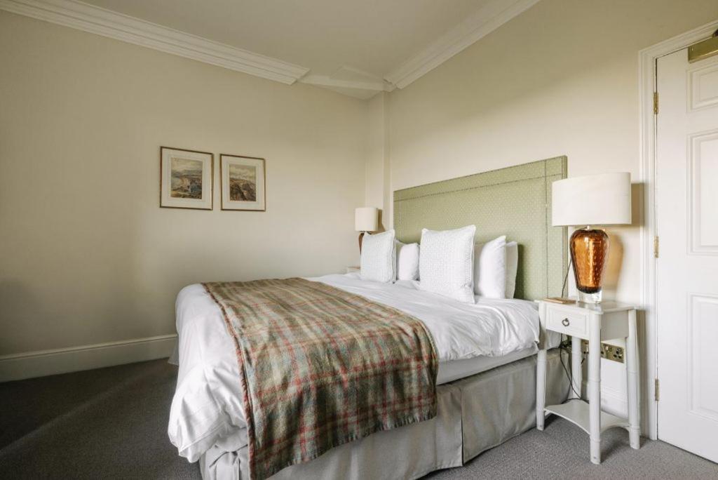 a white bedroom with a bed and a table with a lamp at Victoria in Holkham