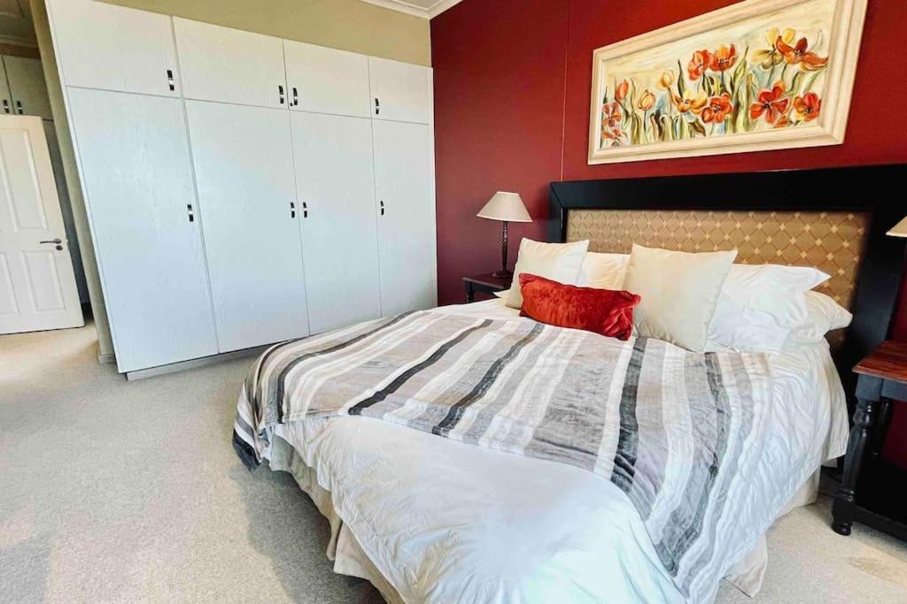 a bedroom with a large bed with a red wall at Lifestyle Villa at Pinnacle in Mossel Bay