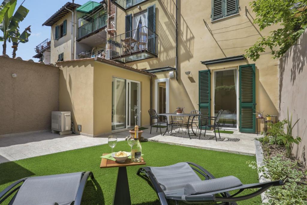einen kleinen Garten mit Stühlen, einem Tisch und einem Gebäude in der Unterkunft La Piccola Corte - Sweet Dreams in Florence in Florenz