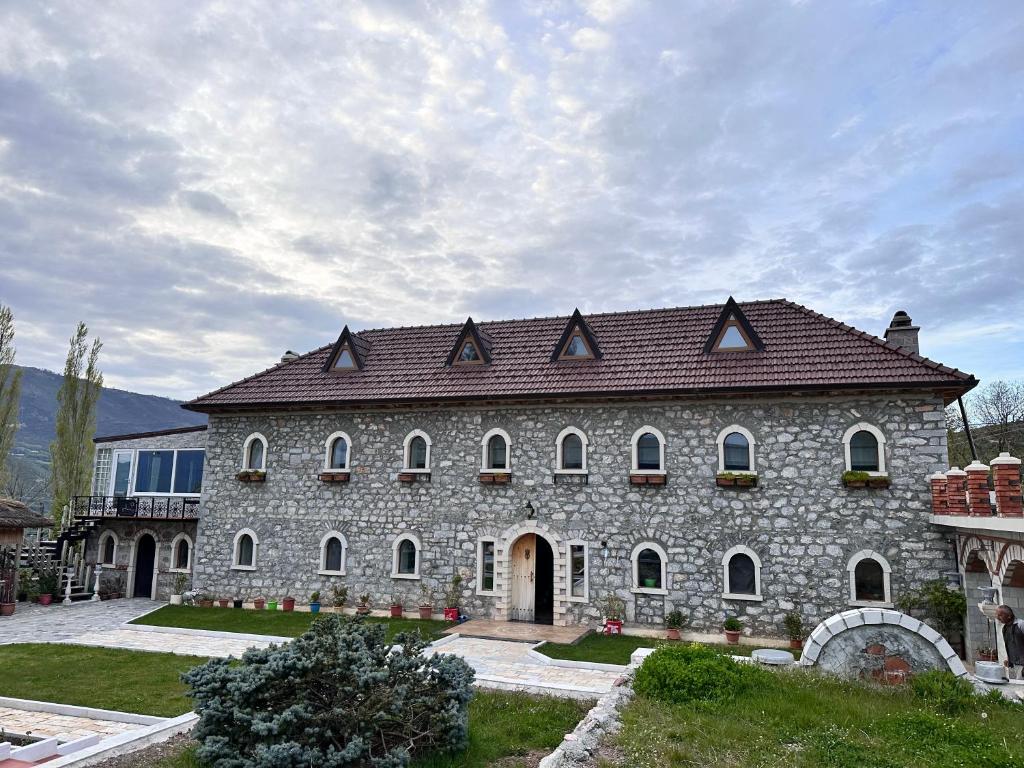 a large stone building with a brown roof at Bujtina Gjana in Kukës