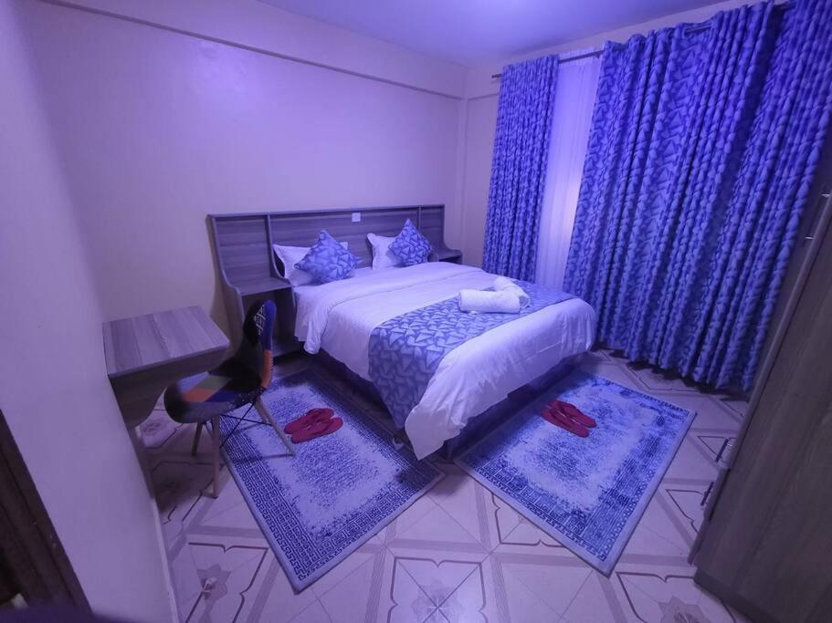 a bedroom with a bed with blue curtains and blue rugs at Blue House 2 Bedroom House. in Naivasha