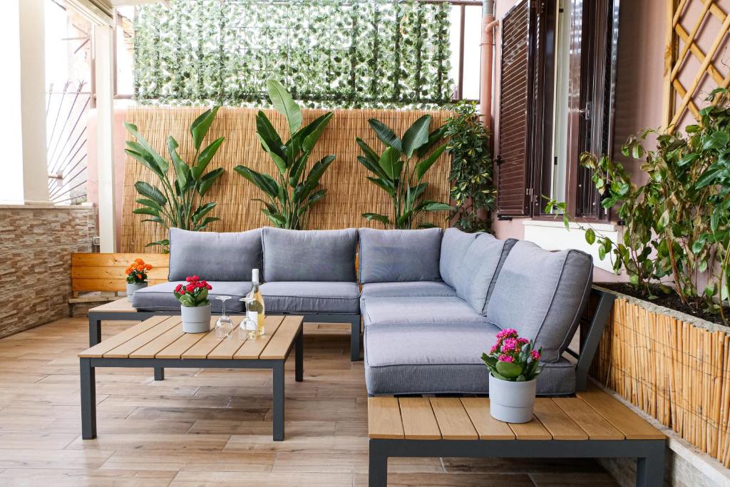 een bank op een patio met 2 tafels en planten bij Hotel Terrazza Magenta in Rome