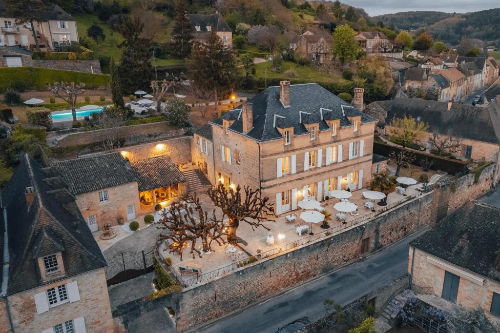 een luchtzicht op een groot gebouw met paraplu's bij Hôtel l'Abbaye in Saint-Cyprien