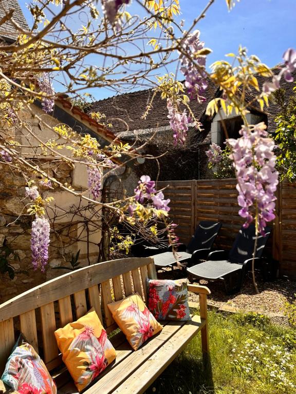 eine Holzbank mit Kissen darauf im Garten in der Unterkunft Le Lavoir aux Roses by Gîtes Sud Touraine in Chédigny