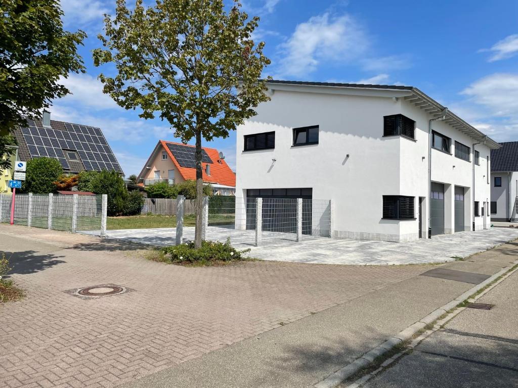 a white building with a tree next to a street at Ferienwohnung OLA in Schwanau