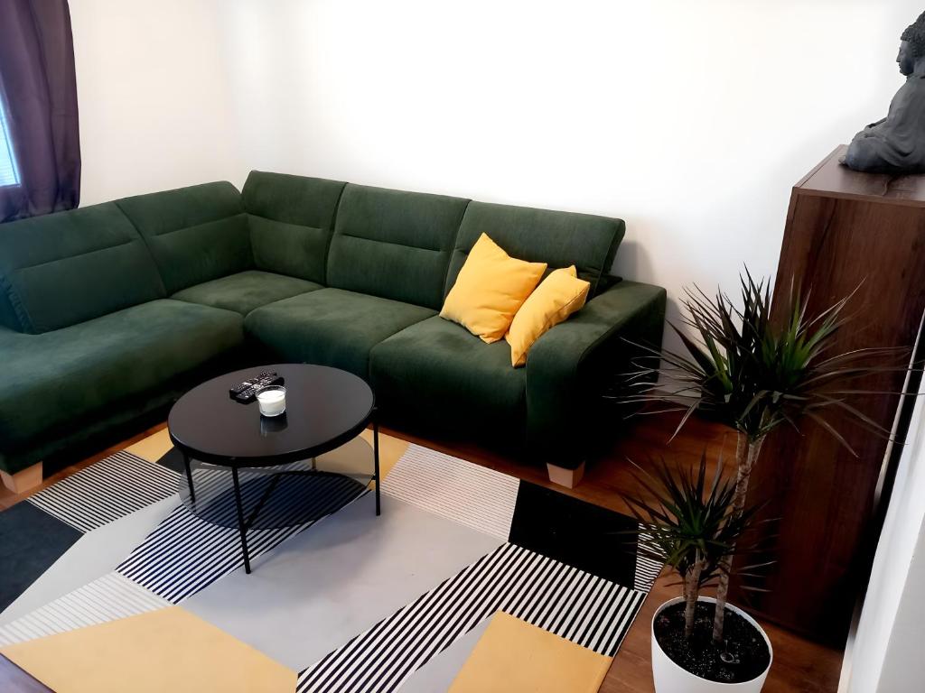 un sofá verde en una sala de estar con mesa en Štýlový apartmán v Šamoríne en Šamorín