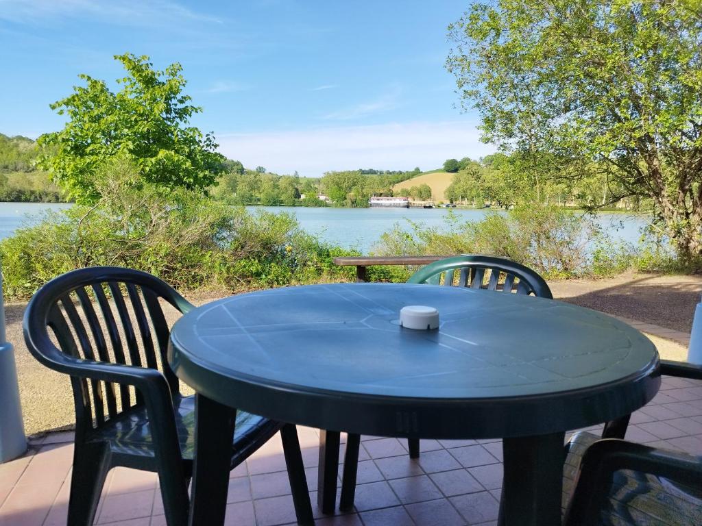 a table and chairs on a patio with a view of a lake at Le petit jazz du lac in Marciac