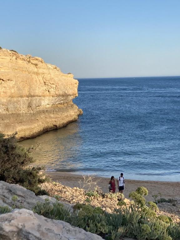 two people walking on a beach near the ocean at 233 Casa Galo Verde Apartments in Porches