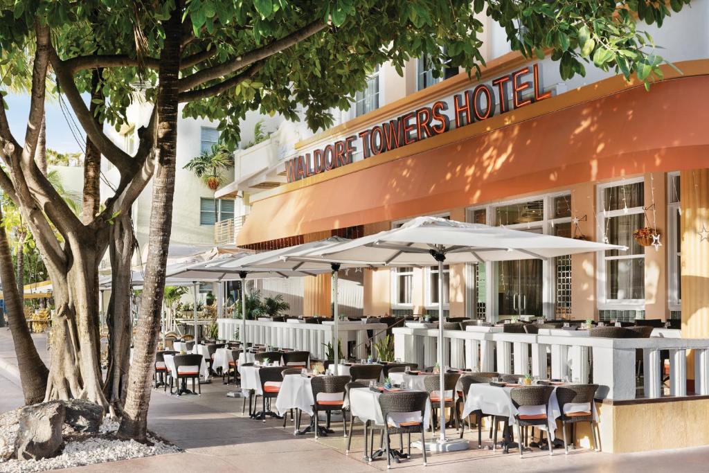 un restaurante al aire libre con mesas, sillas y sombrillas en Waldorf Towers South Beach en Miami Beach