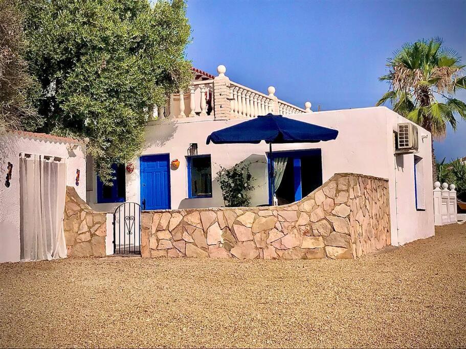 a white house with an umbrella and a stone wall at Casa Alegria Spain Entire Home Private Pool in Antas