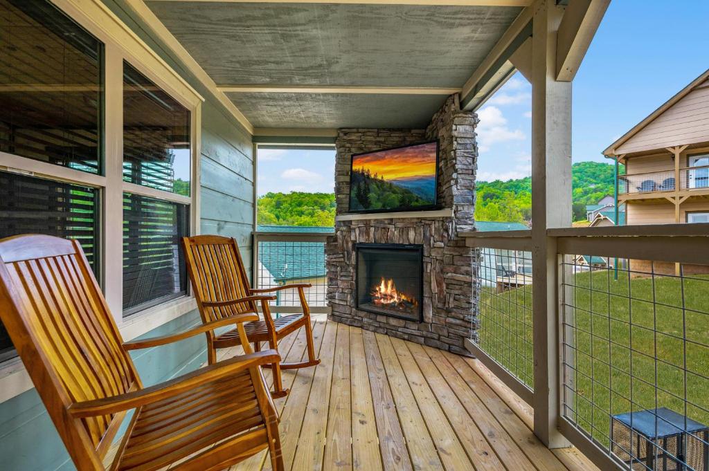 a screened porch with two chairs and a fireplace at Osprey Nest Cottage Modern New Cabin in Pigeon Forge