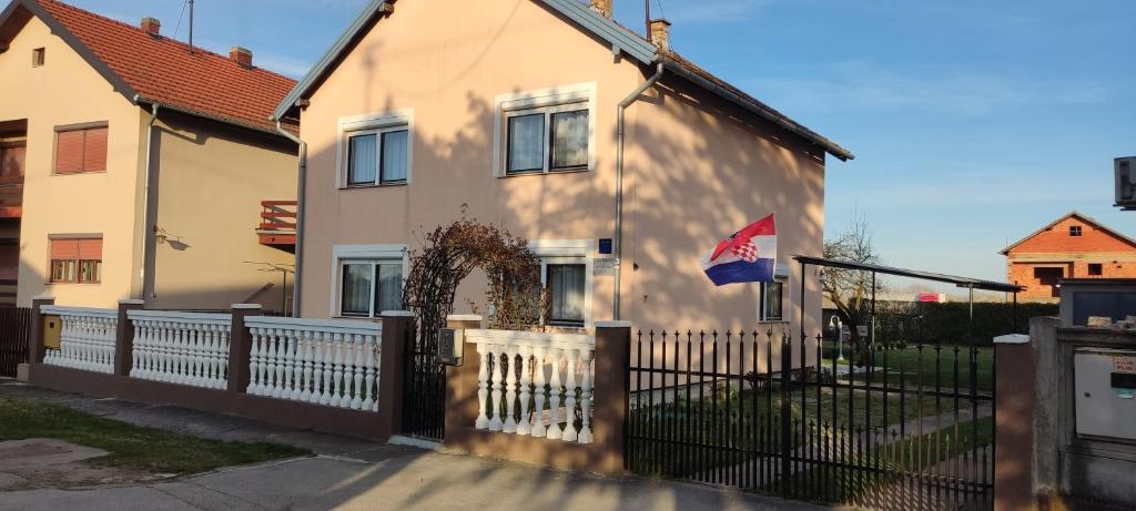 una casa blanca con una valla y una bandera en Apartmani Astra en Vukovar