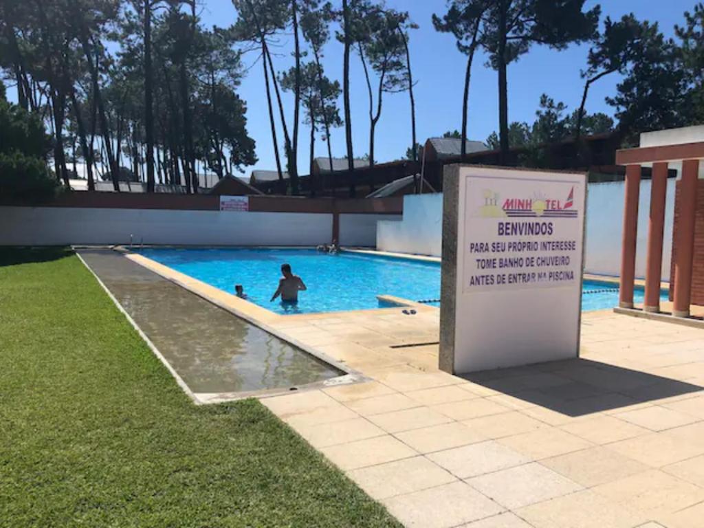 a sign in a swimming pool with a child in the water at Cabedelo BEACH LOFT, quartos em apartamento compartilhado a 5 minutos da praia in Darque