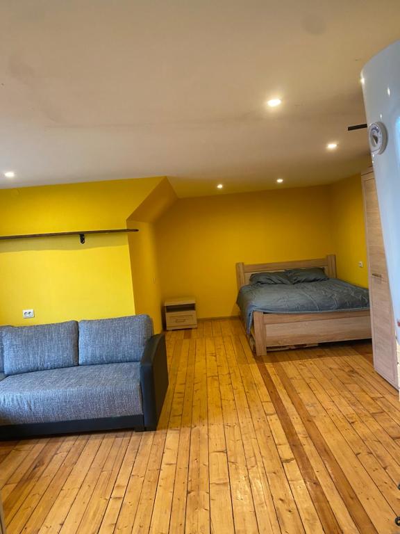 uma sala de estar com um sofá e uma cama em Aņutas flat em Saldus