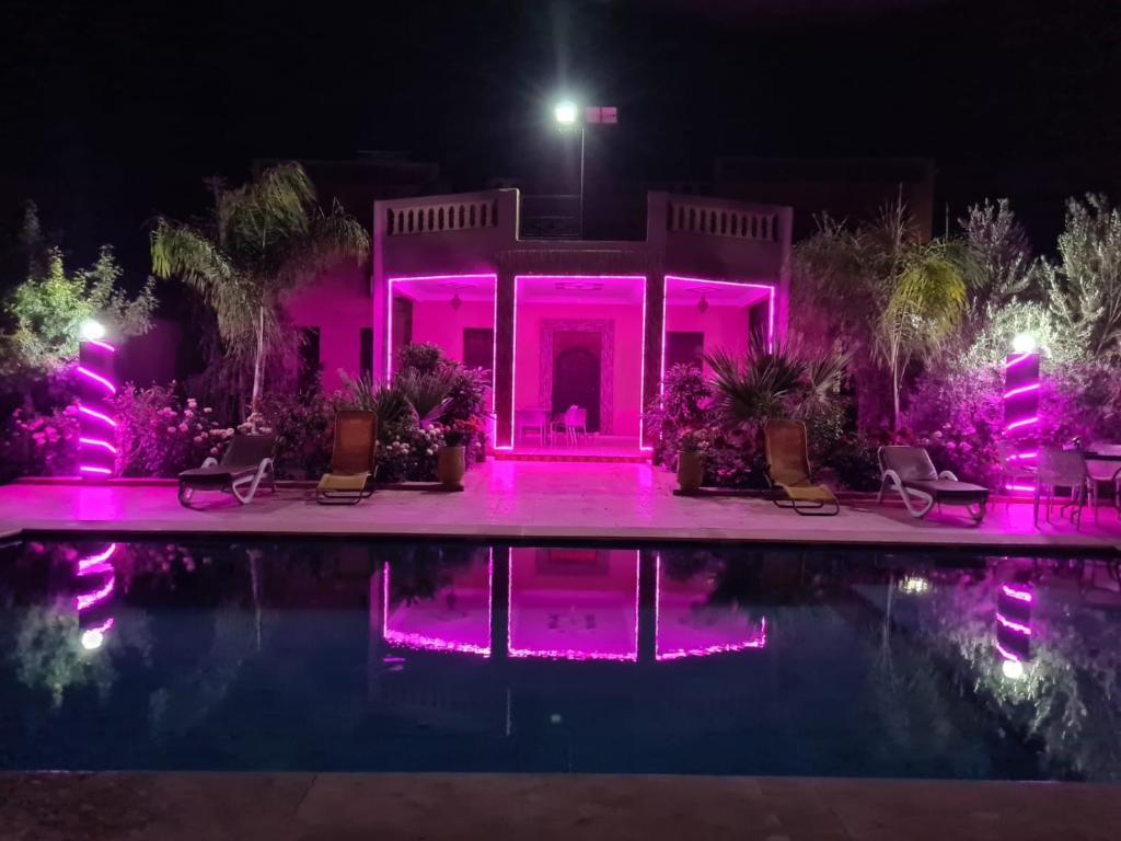 een huis met roze lichten rond een zwembad 's nachts bij Villa Chouiter Center in Marrakesh