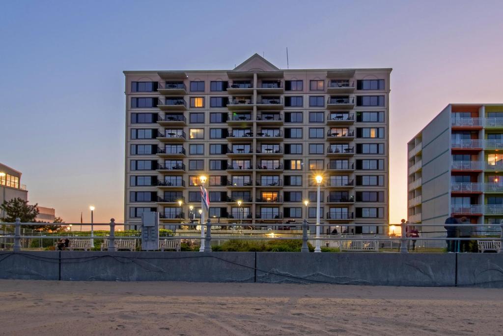 un edificio de apartamentos alto por la noche con edificios en The Colony at Virginia Beach by TripForth en Virginia Beach