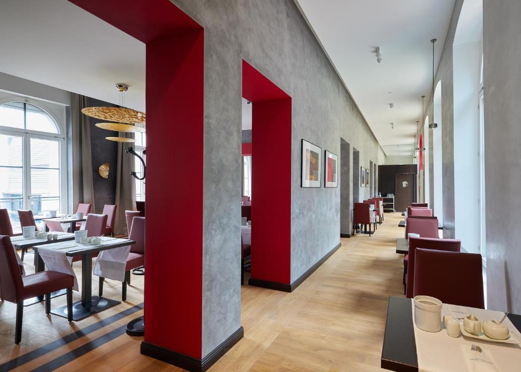 a restaurant with red columns and tables and chairs at Hotel Alte Post in Konstanz