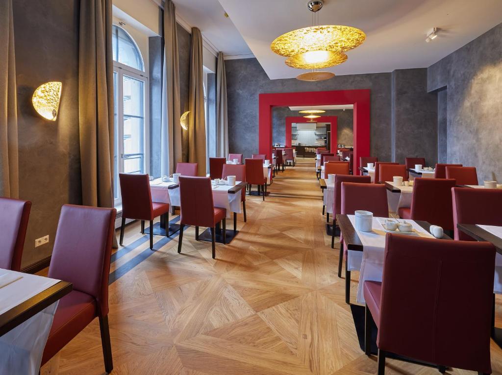 a dining room with tables and red chairs at Hotel Alte Post in Konstanz