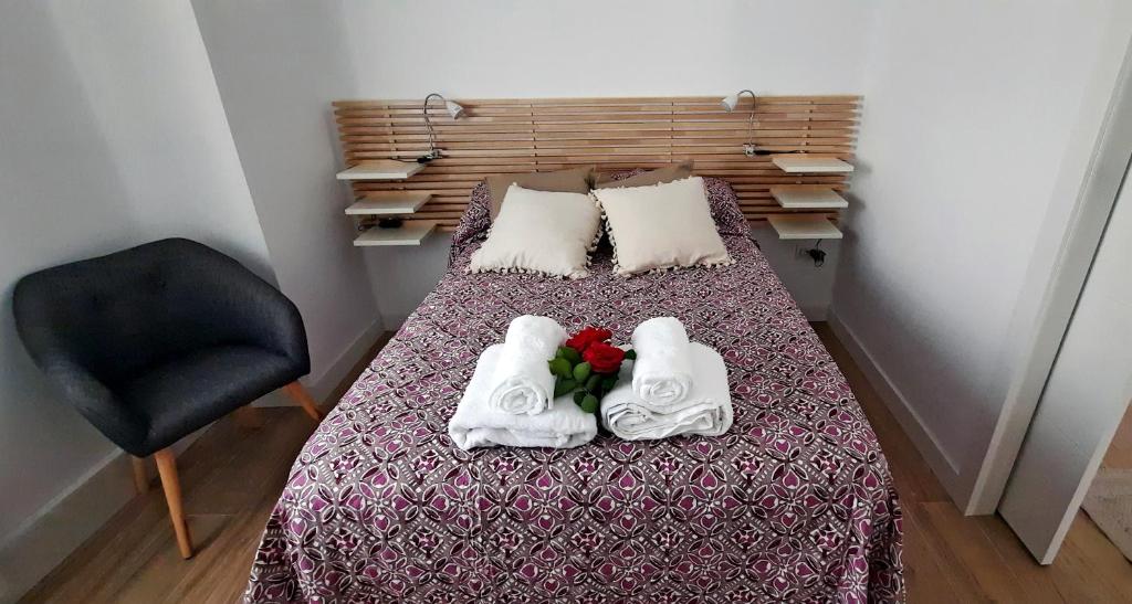a bedroom with a bed with towels and a chair at Kataenea. Apartamento en el prepirineo navarro. Naturaleza in Aoiz