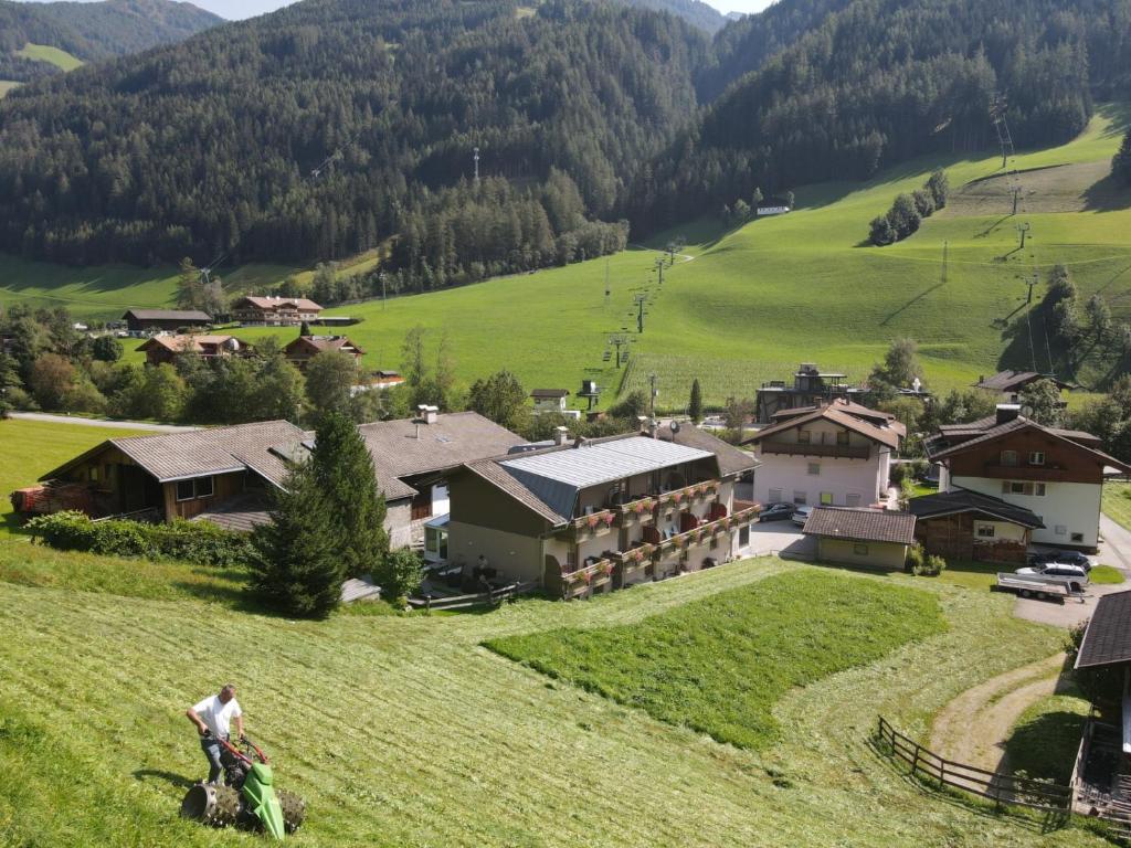 a person riding a horse in a field with a house at MOUNTAIN ALPIN Hotel Sonnleiten in Cadipietra