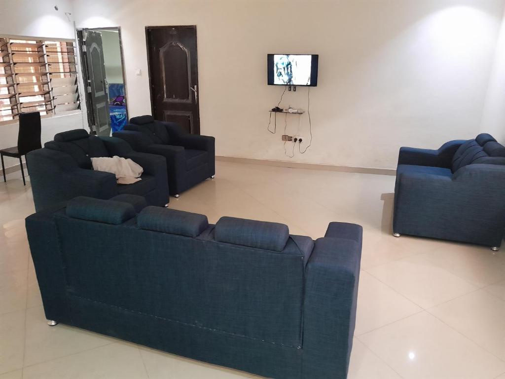 a living room with two blue couches and a tv at Jiso Family Apartment in Tamale