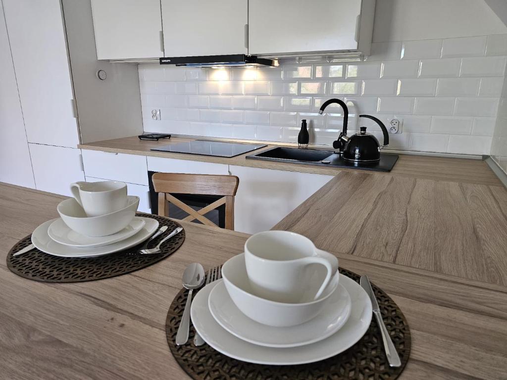 a kitchen with two bowls and plates on a table at Apartament w sercu Oliwy in Gdańsk