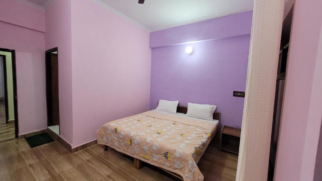een kleine slaapkamer met paarse muren en een bed bij Hotel Aashirwad in Chamoli