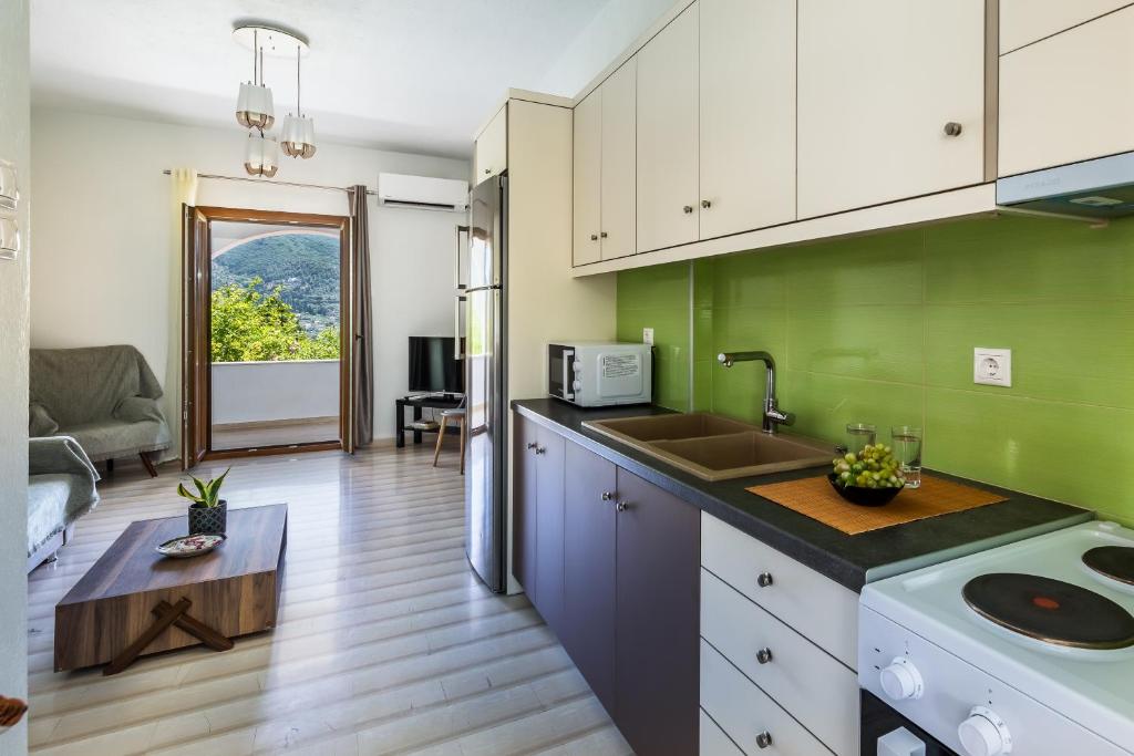 a kitchen with green walls and white cabinets at Lina apartments in Skopelos Town