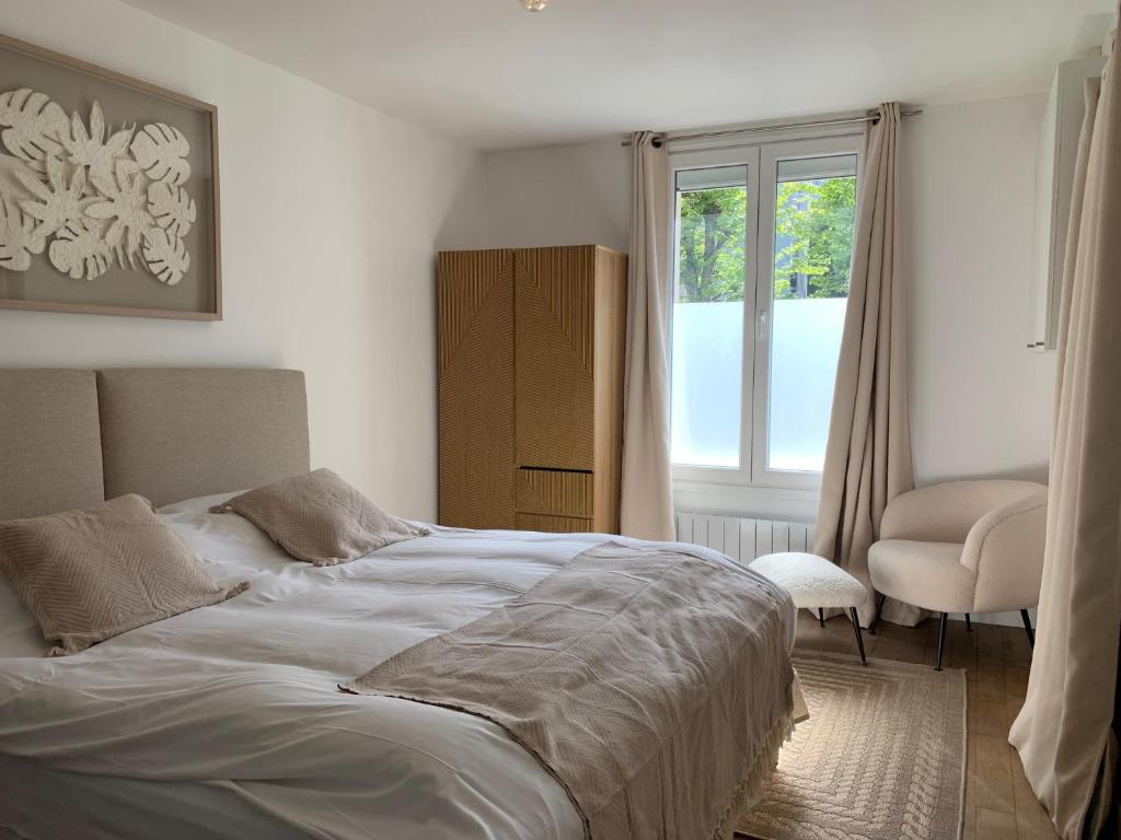 Un dormitorio con una cama grande y una ventana en Les Suites de Vanves - Parc des expositions Porte de Versailles en Vanves