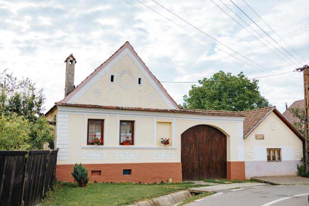 RucărにあるCasa Tradițională Transilvăneanaの茶色の扉のある小さな白い家