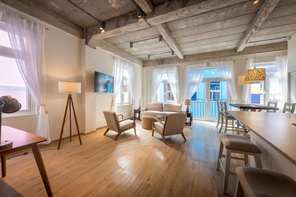 a living room with chairs and a table and some windows at Downtown Dreamstay, Classic 2BR Suites in Willemstad