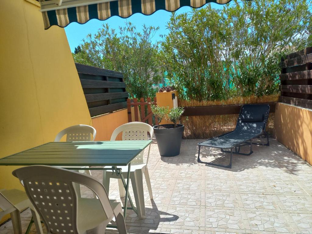 un patio avec des chaises, une table et un banc dans l'établissement Appartement climatisé avec terrasse parking piscine et terrains de tennis, au Cap d'Agde