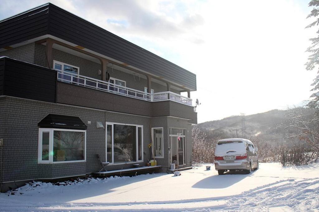 Una furgoneta estacionada frente a una casa en la nieve en Rusutu Ski Chalet - Six Bedrooms, BBQ, Lake Toya., en Rusutsu