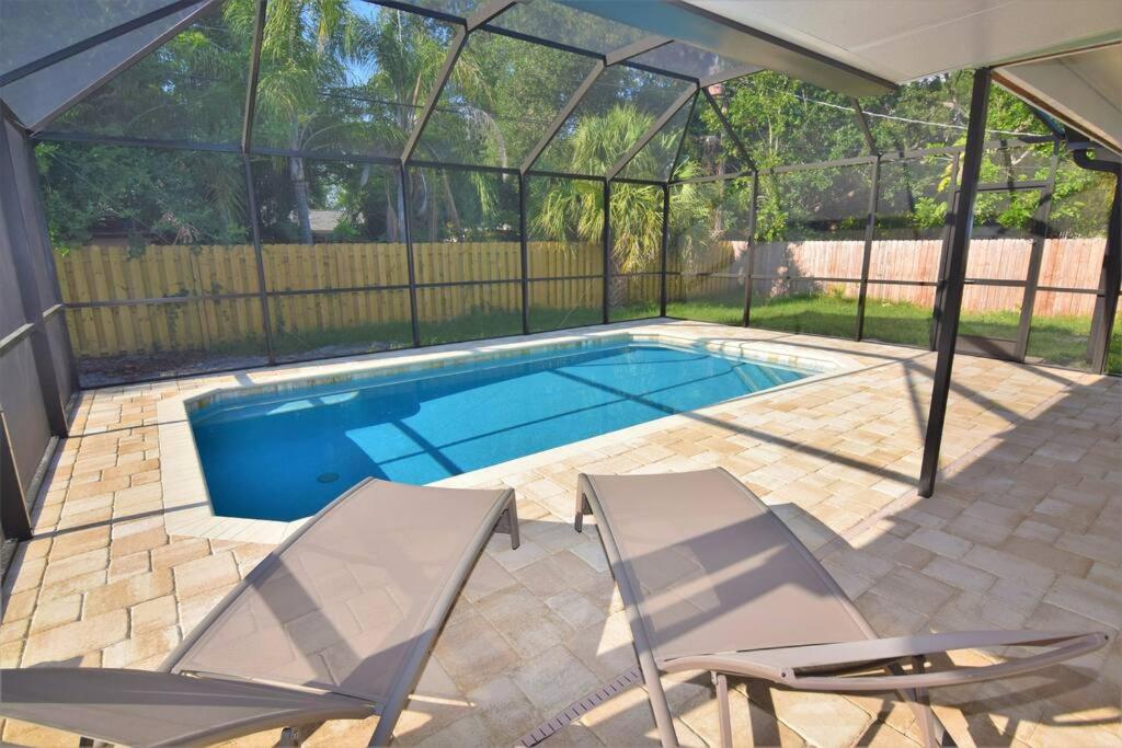 einen Pool mit 2 Stühlen und ein Zelt in der Unterkunft New England 3bd 2bt Home Heated Pool Close to Siesta in Sarasota