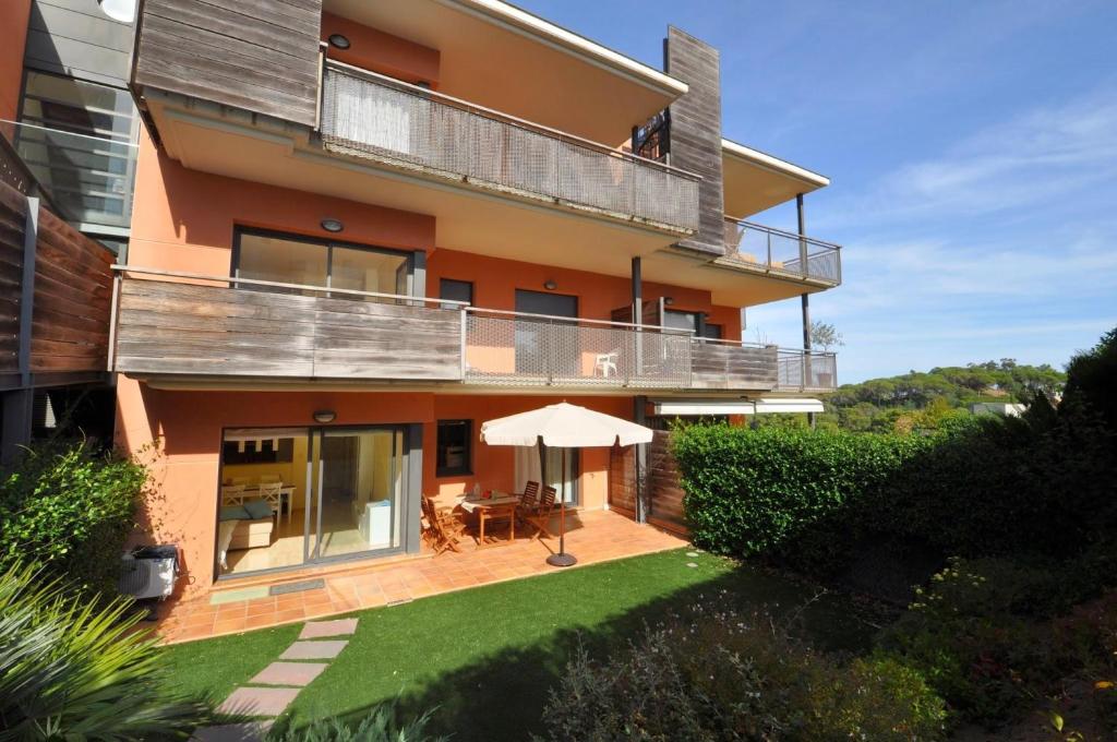 um edifício com uma varanda com uma mesa e um guarda-chuva em Pretty garden apartment next to a charming beach em Lloret de Mar