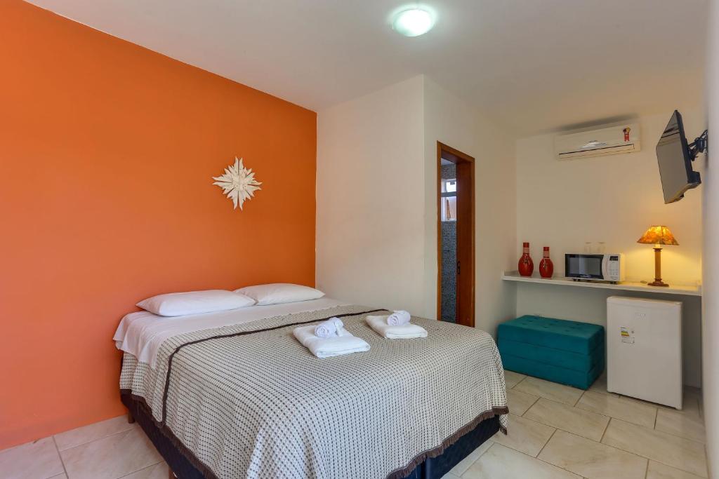 1 dormitorio con 2 camas y pared de color naranja en Apart Carolina, en Florianópolis