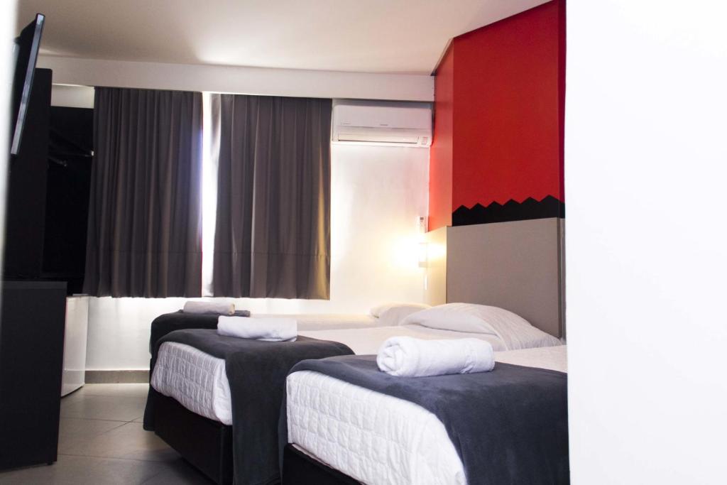 two beds in a hotel room with red and white at Minuano Hotel Express próx Orla Lago Guaíba, Mercado Público, 300 m Rodoviária in Porto Alegre