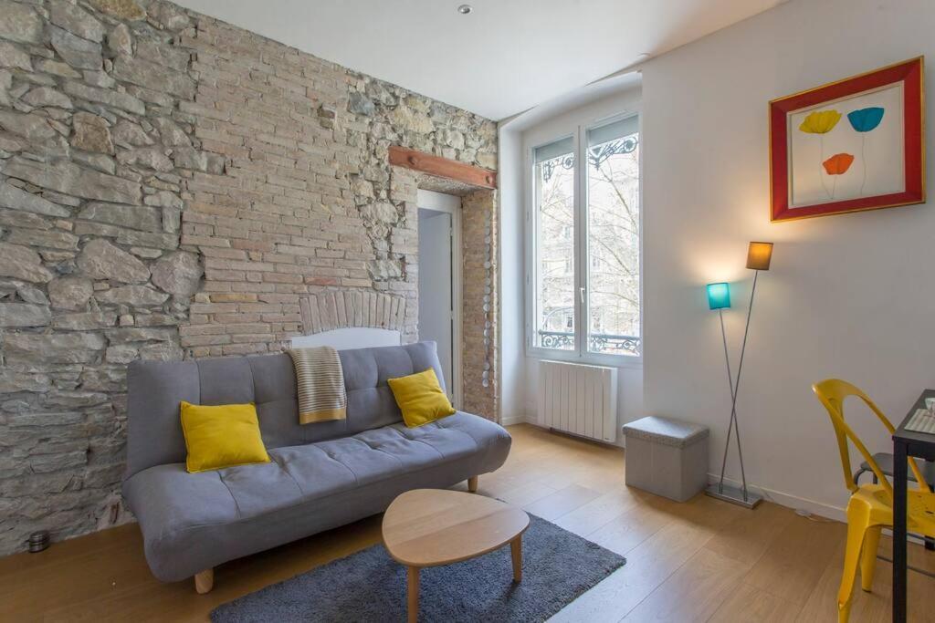 un salon avec un canapé et un mur de briques dans l'établissement Le Jaurès, logement d’exception, à Grenoble