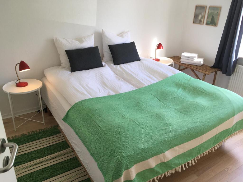 a bedroom with a bed with a green blanket on it at Astas Apartment in Aalborg