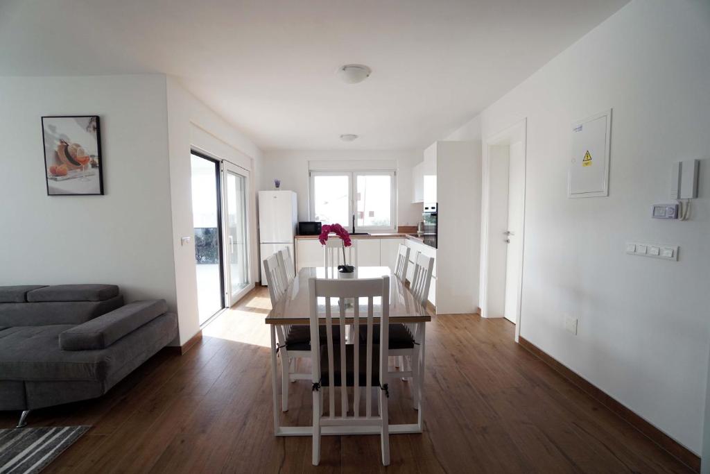 a white living room with a table and a couch at Apartman Petra in Brodarica