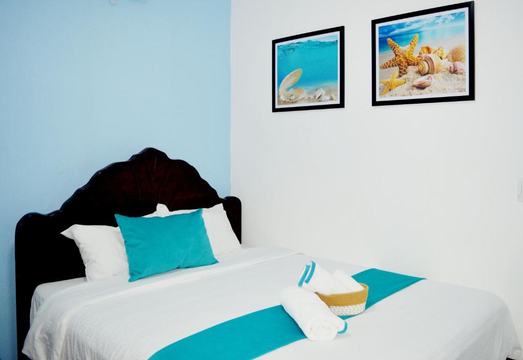 a bedroom with two beds and two pictures on the wall at Apartamento Amueblado Mi Casa Caribe, Santo Domingo a 5 minutos del Aeropuerto Internacional de las Americas in Santo Domingo