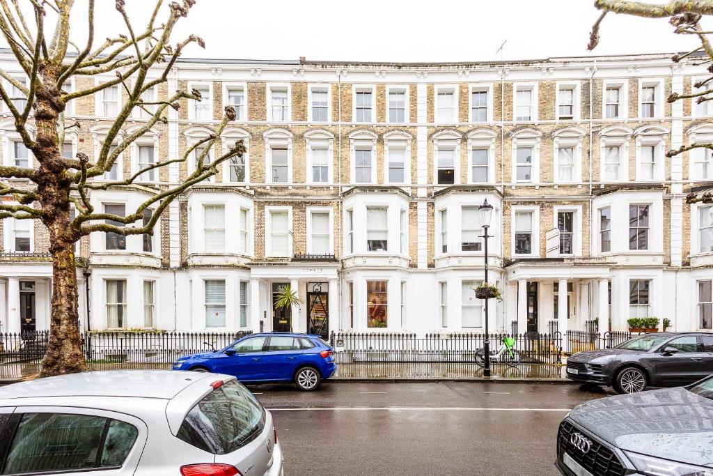 a large white building with cars parked in front of it at Philbeach Gardens Rooms in London