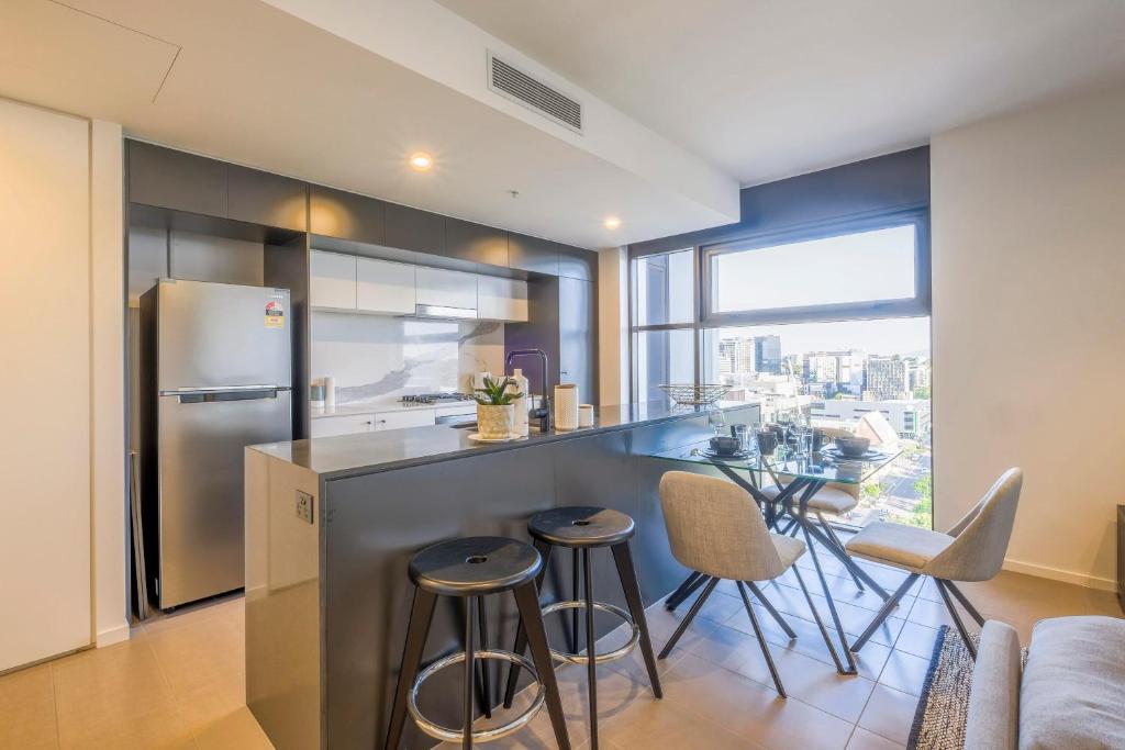 a kitchen with a refrigerator and a table with stools at Stunning Modern and Central 1BdR Apt at South Bank in Brisbane