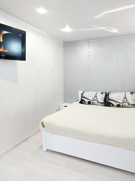 a white bedroom with a bed and a tv on the wall at Lux apartment Sadovaya street in Mykolaiv