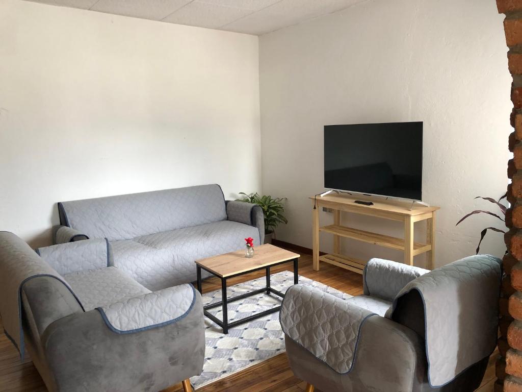 a living room with a couch and a tv at Suite Bellavista Cuenca in Cuenca