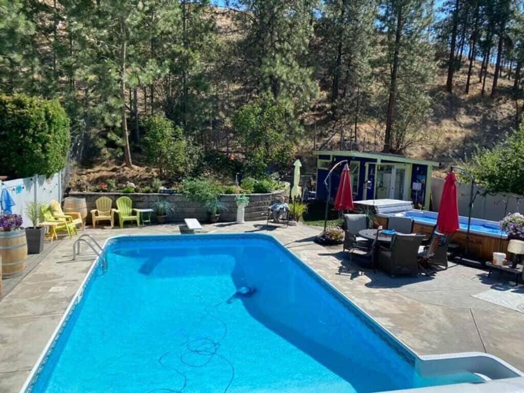 a pool in a yard with a patio and a house at Okanagan Saltwater Pool & Swimspa Oasis in Penticton