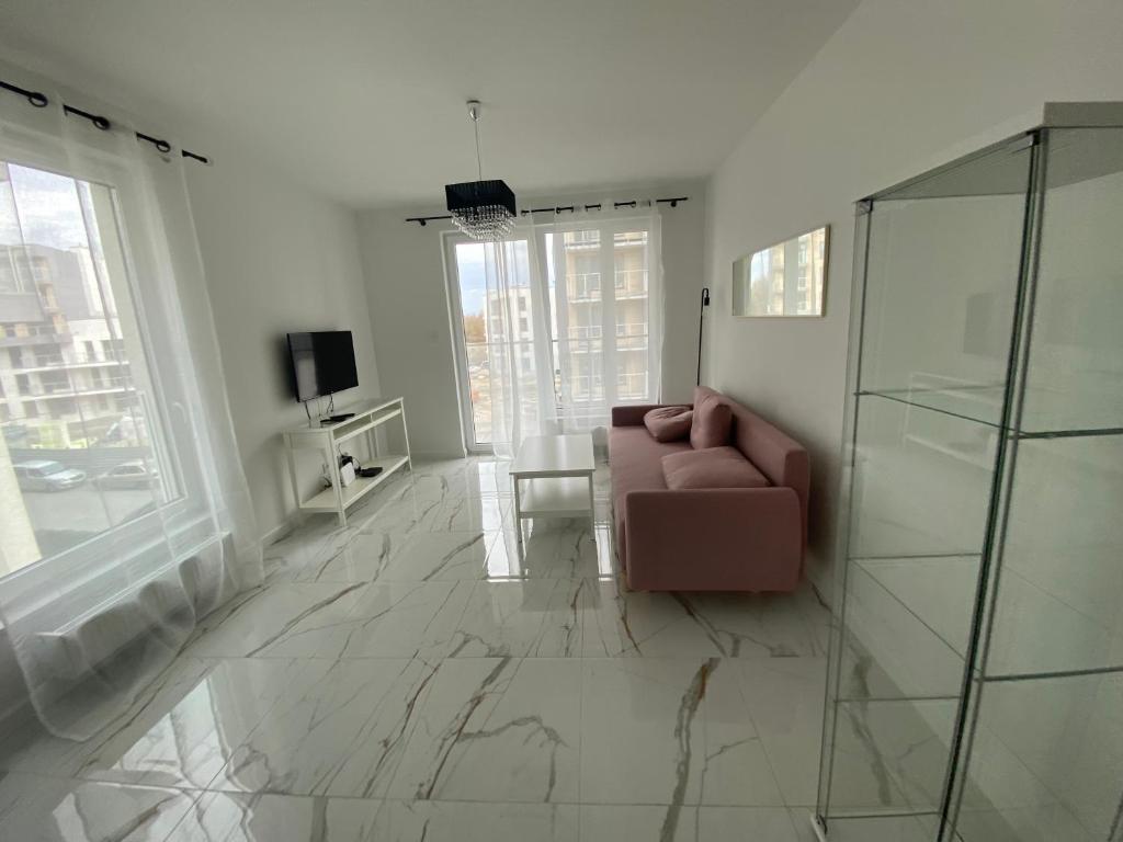 - un salon avec un canapé et une porte en verre dans l'établissement Seaside Apartment, à Gdańsk